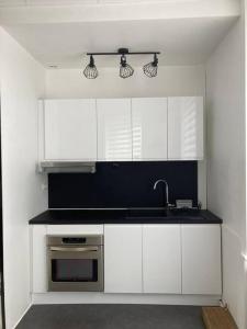 Una cocina con gabinetes blancos y un fregadero. en Black & White Harmony, en Belfort