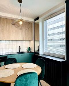 une cuisine avec une table en bois et des chaises vertes dans l'établissement Stańczyka Apartment, à Cracovie