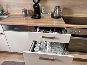 a kitchen counter with an open drawer with cups at Kartels First Appart in Kierspe