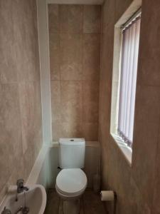 a bathroom with a toilet and a sink and a window at 5 bedroom house - Cheshire Oaks in Ellesmere Port