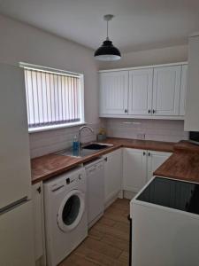 una cucina con armadietti bianchi e lavatrice di 5 bedroom house - Cheshire Oaks a Ellesmere Port