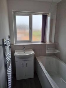 uma casa de banho com um lavatório, uma banheira e uma janela em 5 bedroom house - Cheshire Oaks em Ellesmere Port
