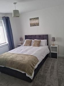 5 bedroom house - Cheshire Oaks في إليسمير بورت: غرفة نوم بسرير كبير وموقف ليلتين