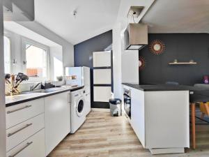 a kitchen with white cabinets and a washer and dryer at Joli T2 Scandi in Riom