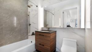 a bathroom with a sink and a toilet and a tub at Lux 2 Bedroom 1 Bath Suite in Hudson Yards in New York