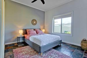 a bedroom with a bed with pink pillows and a window at Seaside on Swan Laneway Retreat in Grange +52 photos