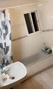 ein Bad mit einem Waschbecken, einer Badewanne und einem Fenster in der Unterkunft Cozy apartment with private pool in Benalmádena