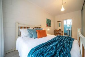 ein Schlafzimmer mit einem großen weißen Bett mit blauen und orangefarbenen Kissen in der Unterkunft Dreamscape on Duthy - WiFi Art in Unley