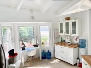 a white kitchen with a desk and a window at Hidden Valley Villa in Teagues Bay