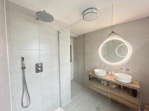 a bathroom with a shower and two sinks and a mirror at No3 Gweek in Gweek
