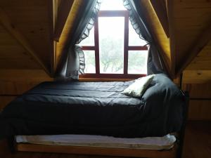 een bed in een kamer met een raam bij Cabañas en los reartes in Los Reartes