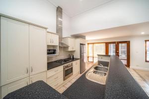 a kitchen with white cabinets and a black counter top at Irmas Place on Halifax in Adelaide