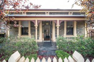 uma casa com uma cerca branca em frente em Irmas Place on Halifax em Adelaide