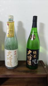 duas garrafas de vinho numa prateleira de madeira em 古民家貸し切り0818変則あり最大10人まで em Gifu