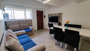 uma sala de estar com um sofá azul e uma mesa em Ao Lado do Aeroporto com Ar Condicionado e vaga coberta em Guarulhos