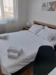 a bedroom with a large white bed with two towels on it at ELI's Apartments in Iaşi