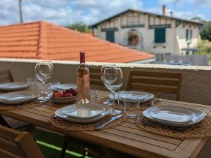 a wooden table with a bottle of wine and glasses at Bisc'Appart standing et calme à 250 m de la plage in Biscarrosse