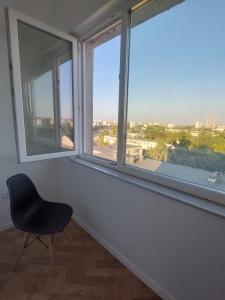 a black chair sitting in a room with windows at ELI's Apartments in Iaşi