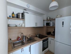 a kitchen with white cabinets and a sink and a refrigerator at Bisc'Appart standing et calme à 250 m de la plage in Biscarrosse +16 photos