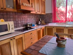 eine Küche mit Holzschränken und einem Tisch mit Mikrowelle in der Unterkunft A 5 MINUTI DA TRAPANI e FREE PARKING in Torre Nubia