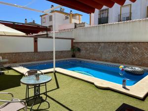una piscina en un patio trasero con una mesa y una mesa en Casa con piscina cerca de Sevilla, en Sevilla