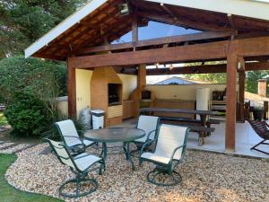a patio with a table and chairs and a grill at Casa Campos do Jordão, bairro Capivari, Wi-Fi, churrasqueira e forno de pizza, totalmente equipada in Campos do Jordão