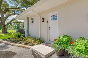 une maison blanche avec une porte blanche et quelques fleurs dans l'établissement Cozy Ocala Retreat with Pool, Screened Lanai!, à Ocala