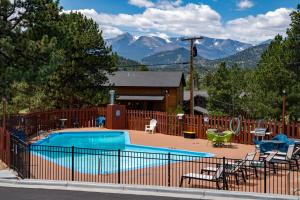 une piscine avec des chaises et une maison avec des montagnes dans l'établissement Hotel Estes, à Estes Park