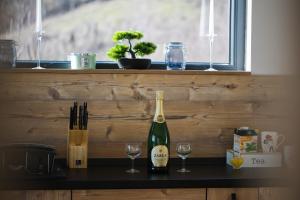 a bottle of wine and two glasses on a counter at Infinity Cabin in Râșca