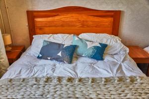Bett mit weißer Bettwäsche und blauen Kissen in der Unterkunft Hostal Triwe in Puerto Octay