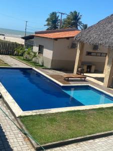 a blue swimming pool next to a house and the beach at Beira-mar Chalé Maceió - Camocim in Maceio