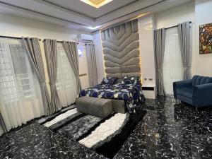 a bedroom with a large bed and a blue chair at Luxury 4 bedroom duplex in Lekki