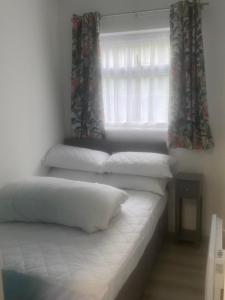 um quarto com 3 almofadas numa cama com uma janela em Ground floor apartment Brean em Brean