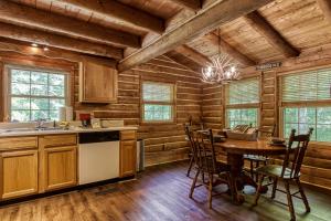 a kitchen with wooden walls and a table and chairs at VERY private, real log cabin with hot tub! in Sevierville