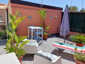 eine Terrasse mit Pflanzen, einem Tisch und einem Sonnenschirm in der Unterkunft Galena Charme Luxury Terrace in Syrakus