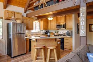 a kitchen with wooden cabinets and a stainless steel refrigerator at High Sierra Cabin with Grill, Serene Location! in Twain Harte