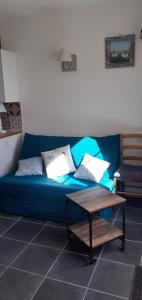 un sofá azul con almohadas y una mesa en una habitación en L'Escale Cotinarde en La Cotinière