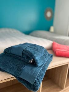 a pile of blue towels sitting on a bed at À la campagne, studio 25M2-pour 2p, CALME, wifi, jardin, parking in Yèvres