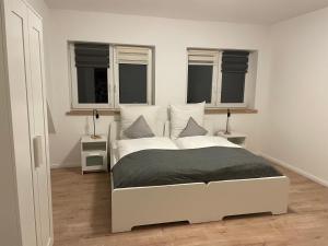 un letto bianco in una stanza con due finestre di Ferienwohnung Wintermoor a Schneverdingen