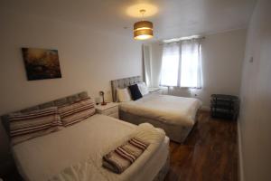 1 dormitorio con 2 camas y ventana en Garden Court en West Drayton