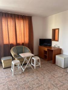 a room with a chair and a table and a tv at Къща Нанси in Sunny Beach