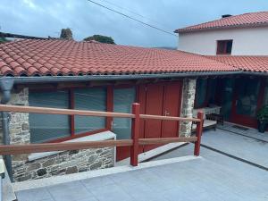 ein Haus mit roten Türen und einem Holzzaun in der Unterkunft Casa do Crego 