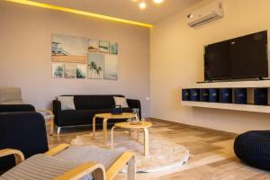 a living room with a couch and a flat screen tv at The little Cottage Chalet- B3 in Amman