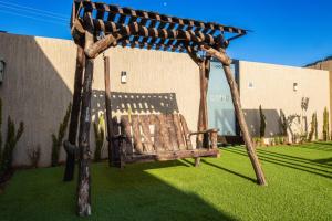 a wooden swing in a yard with green grass at The little Cottage Chalet- B3 in Amman
