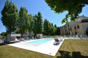a swimming pool with lounge chairs and a building at Kyriad Dijon Est Mirande in Dijon
