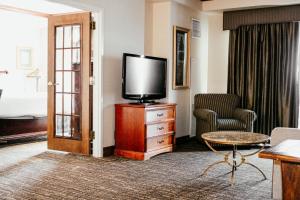 una camera d'albergo con TV, divano e tavolo di Hotel Topeka at City Center a Topeka