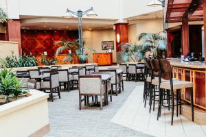 a restaurant with tables and chairs and a bar at Hotel Topeka at City Center in Topeka