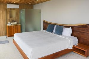 a bedroom with a large white bed with blue pillows at Casa Sulit in Dominical