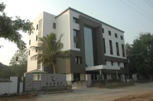 un edificio con una palmera delante de él en Hotel Kanan en Ahmedabad