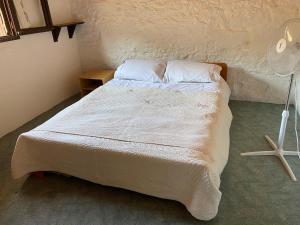 Cette chambre comprend un lit avec des draps blancs et un ventilateur. dans l'établissement La Bergerie, with private pool and garden, à Lodève
